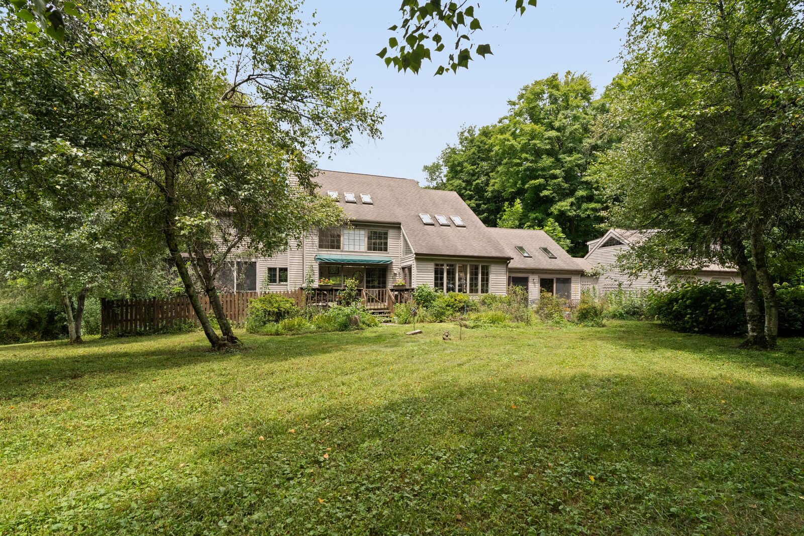 The house seen across the mowed clearing, low and wide against the tree line