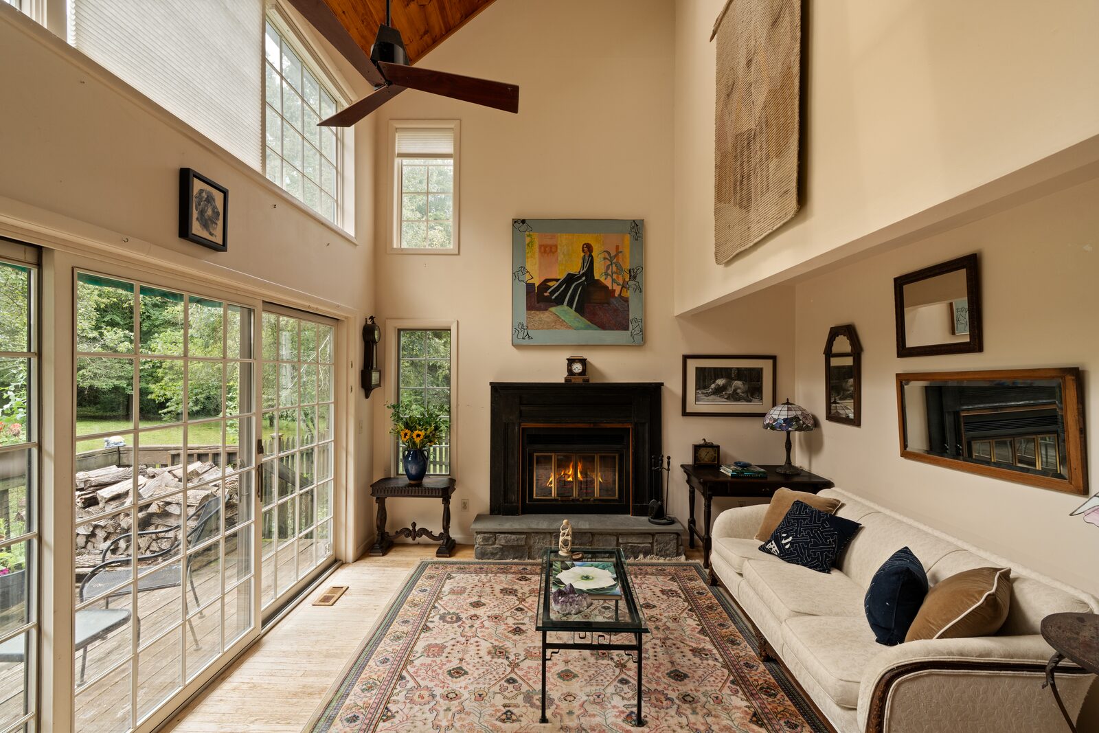 The great room from the opposite end, forest through the glass and the hearth beyond