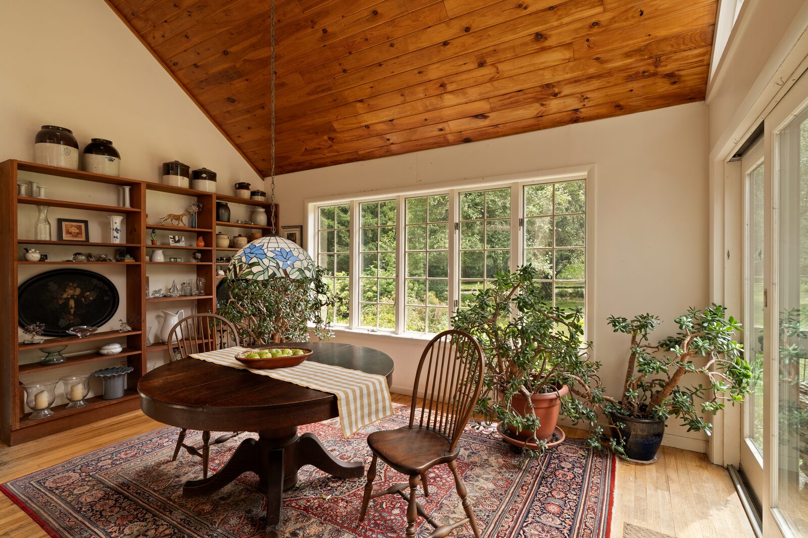 The dining room under a pine vault, windows on two sides and morning light low across the floorboards