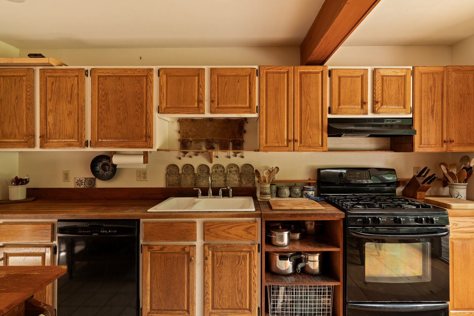 The kitchen — tile underfoot, a range and sink set under wood cabinetry