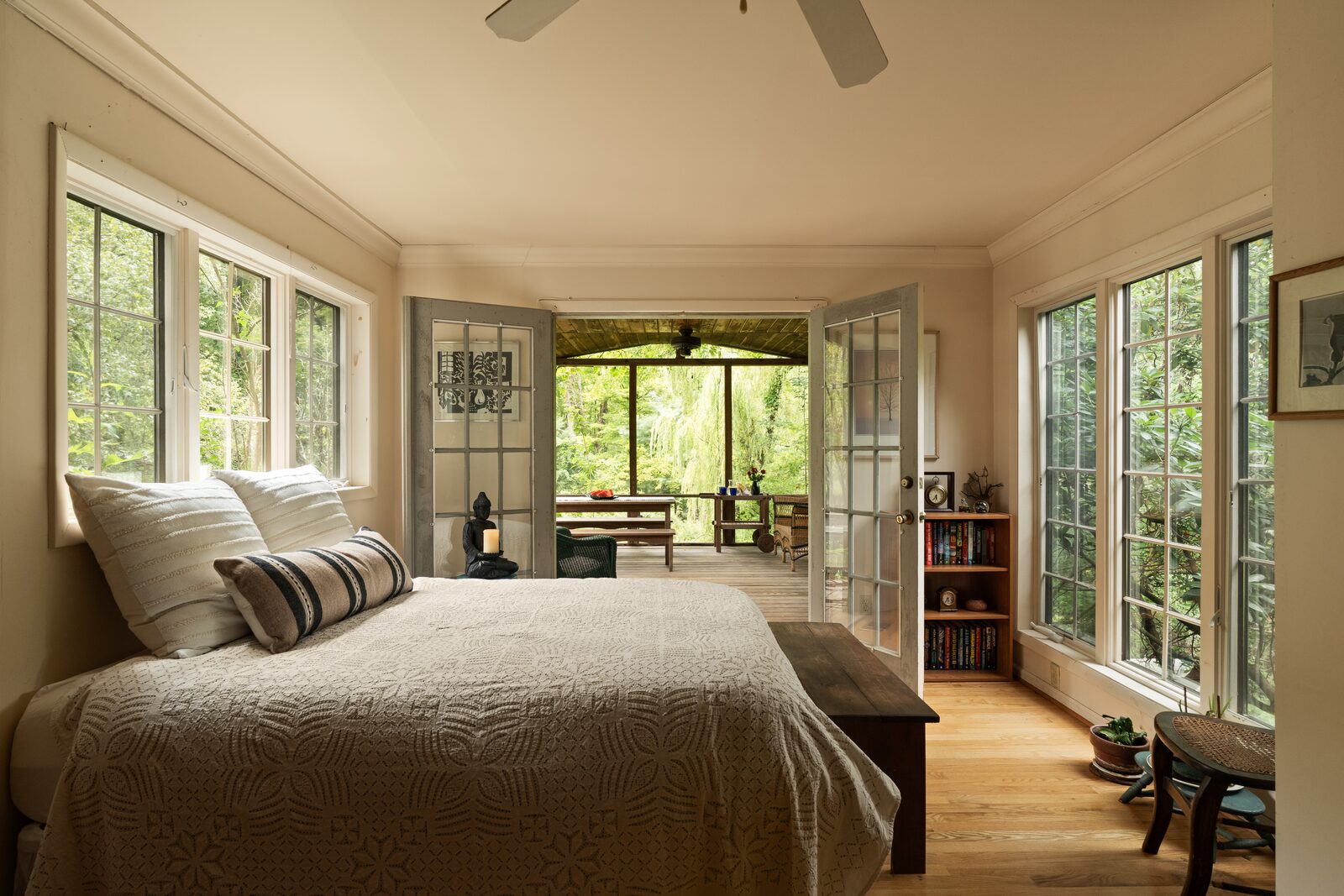 A bedroom with windows on two sides and French doors to the screened porch