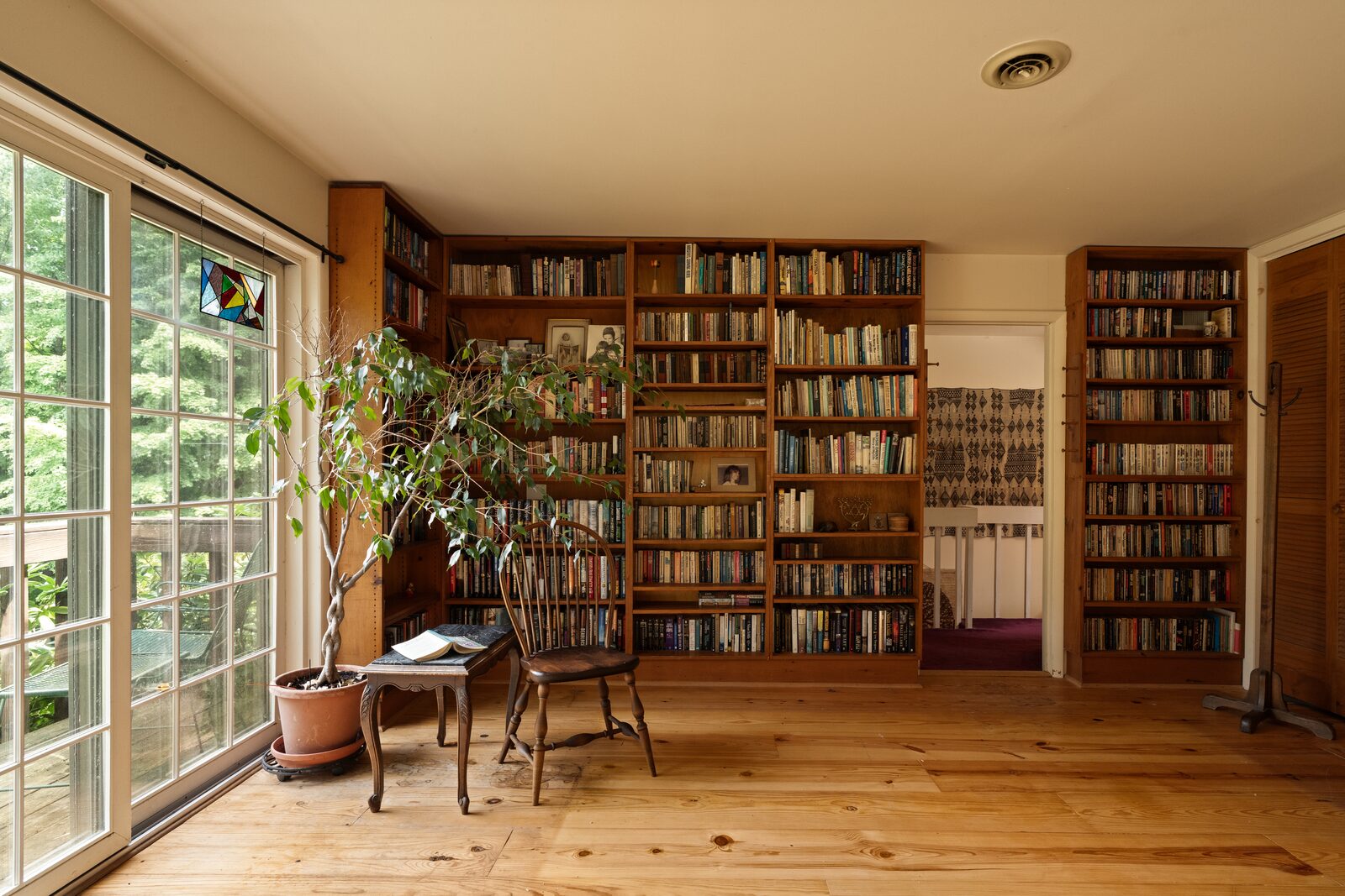 The library — floor-to-ceiling shelves on two walls, with French doors onto a balcony above the trees