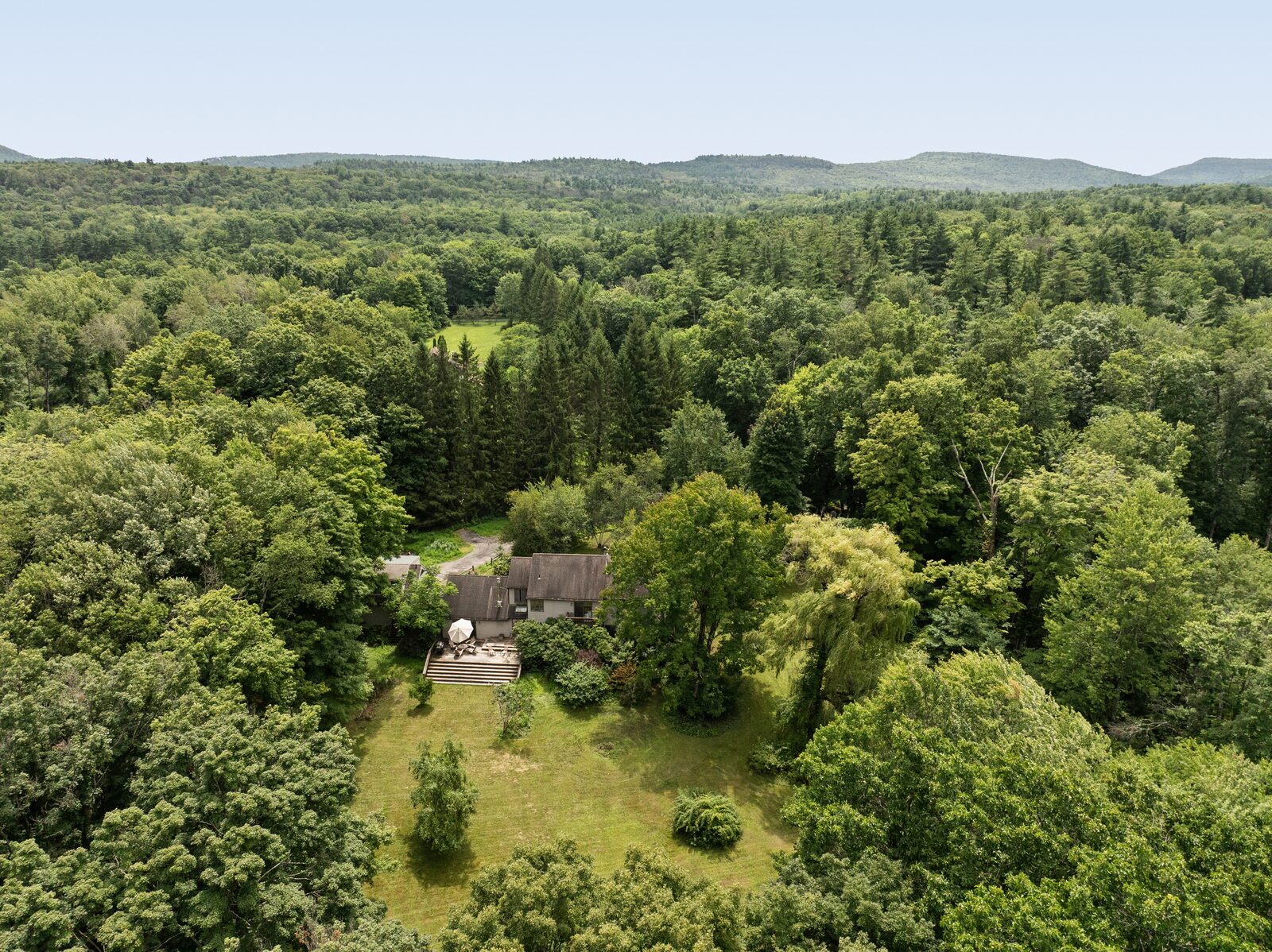 From the air — the clearing, the house, and the ridge laid across the horizon