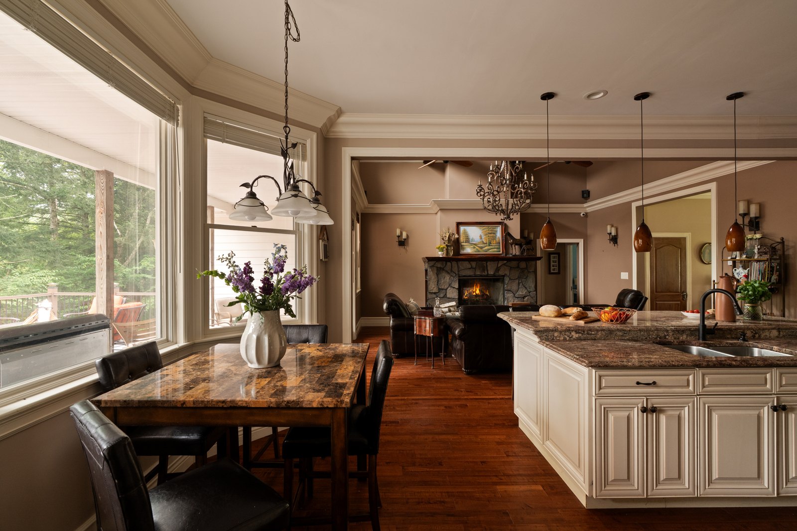 A kitchen island and dining table beneath tall windows.