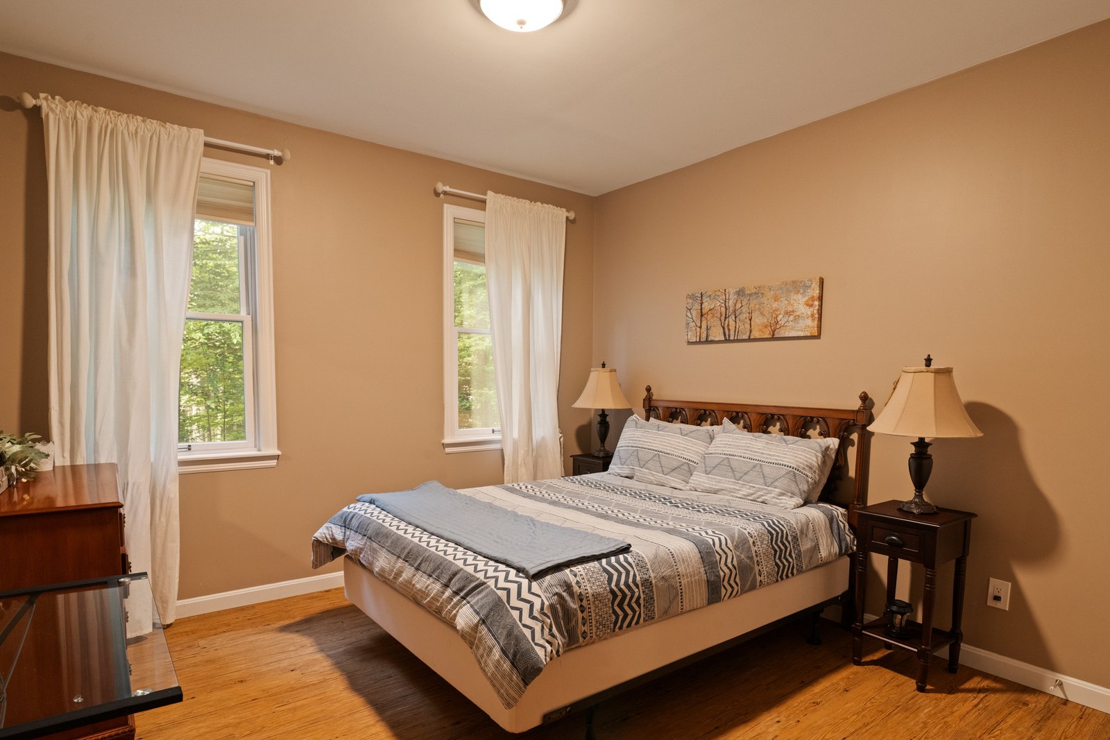 A bedroom with a bed, side tables and a curtained window.